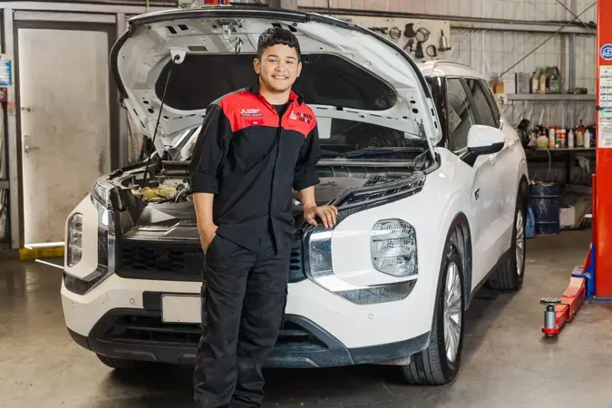 Apprentice standing in front of car with bonnet open