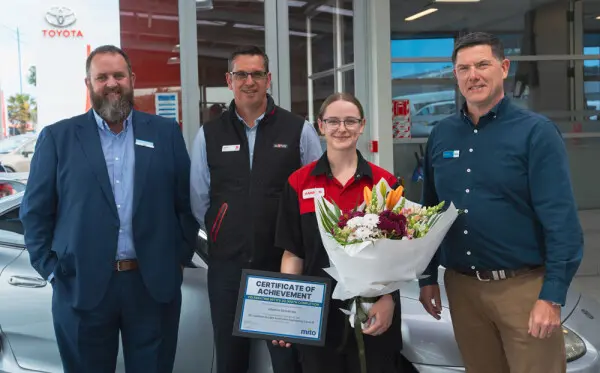 Hannah Bashford holding flowers with her certificate of achievement, celebrating MITO's 30,000th completion.