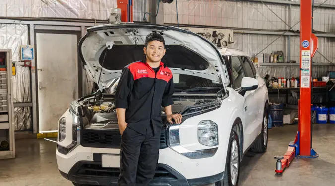 Ali Mirzada smiling, leaning on a car in a workshop