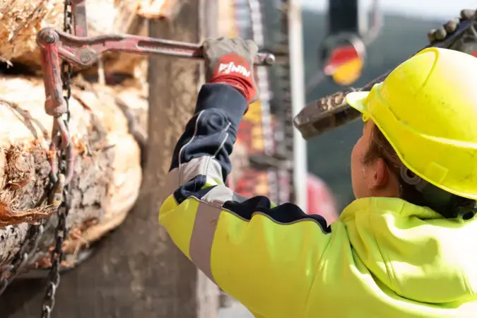 Worker wrenching chains on a logging truck
