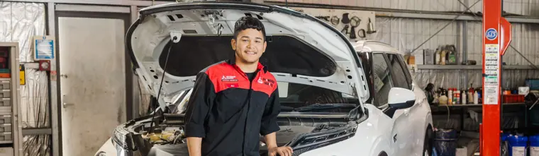 Ali Mirzada smiling, leaning on a car in a workshop